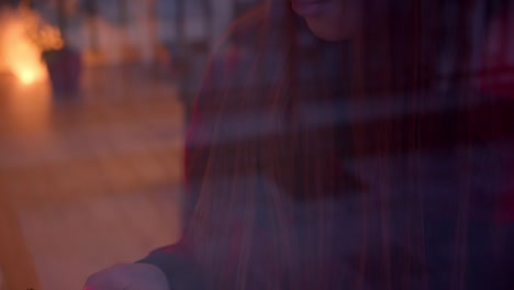 Red-haired-teenage-girl-at-the-window-uses-a-smartphone-Christmas-reflection-Coziness