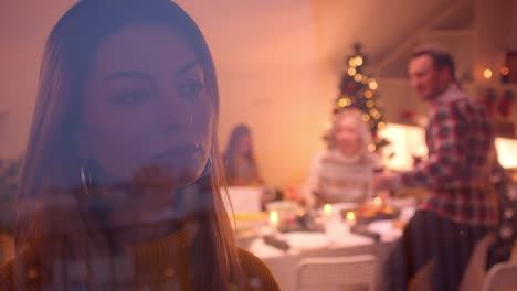 Ehemann-und-Frau-lächeln-und-Eltern-schauen-aus-dem-Fenster-Weihnachtsessen-hinter-Glas-Eltern