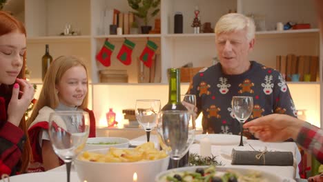 Family-sitting-at-table-Christmas-grandfather-head-of-granddaughter-family-redhead-girl