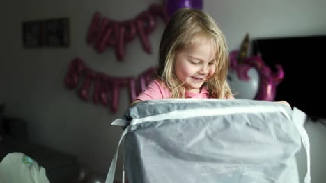 Blond-little-girl-opens-the-gifts.-Child-looks-in-the-box,-is-surprised