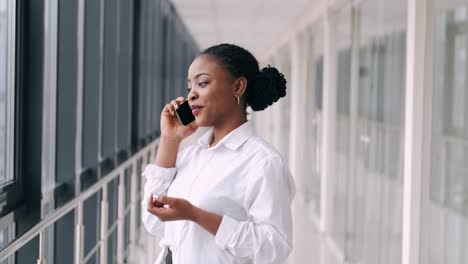 African-American-woman-is-talking-on-the-phone-and-smiling-at-the-airport