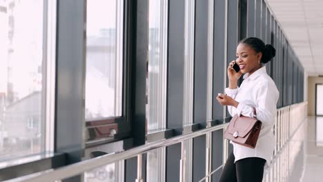 Young-dark-skinned-woman-with-a-bag-is-talking-on-the-phone