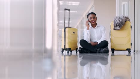 Woman-with-suitcases-is-sitting-in-the-airport-hall-and-taking-selfies