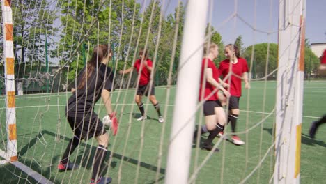 Jugadoras-de-fútbol-femeninos-anotando-gol-durante-el-partido-al-aire-libre