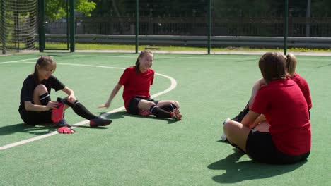 Junge-Fußballerinnen-chatten-auf-dem-Rasenplatz