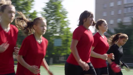 Jóvenes-jugadoras-de-fútbol-femeninos-haciendo-levantamiento-de-talón-corriendo