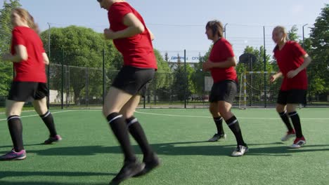 Weibliche-Fußballsportler-üben-seitlichen-Lauf-auf-dem-Feld-während-des-Trainings