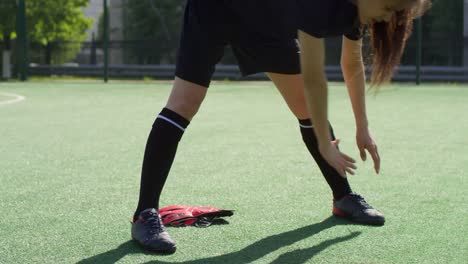 Young-Female-Soccer-Athlete-Stretching-on-Green-Field