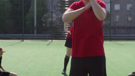 Joven-jugadora-de-fútbol-femenina-haciendo-ejercicio-con-compañeros-de-equipo-al-aire-libre