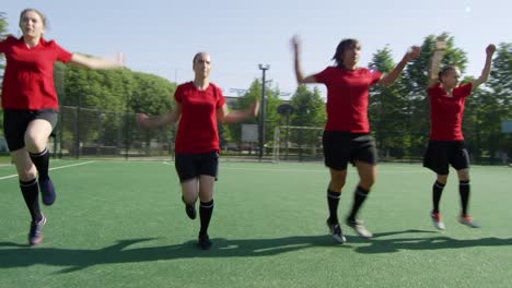 Weibliche-Fußballerinnen-wärmen-sich-für-das-Training-auf-dem-Feld-auf