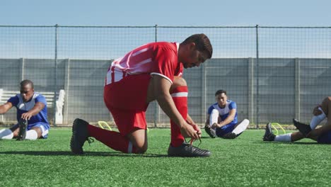 Futbolistas-atezando-sus-zapatos-en-el-campo