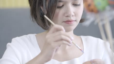 Portrait-of-cheerful-happy-girl,-painting-on-fantasy-easter-eggs-with-a-brush-beautiful-decorative-and-colourful-of-handmade.-Holidays-and-people-the-symbolic-of-Easter-egg-festival-concept.