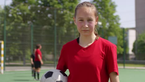 Junge-Fußball-Mädchen-Holding-Ball-und-posiert-für-Kamera