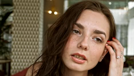 Smiling-russian-woman-looking-out-while-sitting-in-a-quiet-metropolitan-cafe-with-soft-natural-lighting.-Medium-close-up-shot-on-4k-handheld