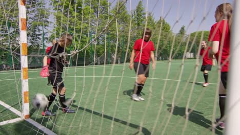 Blick-durch-Das-Fußballnetz-der-weiblichen-Mannschaft,-die-auf-dem-Spielfeld-spielt