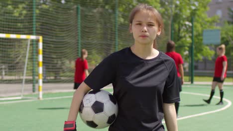 Joven-mujer-portero-posando-para-la-cámara-con-el-balón-de-fútbol