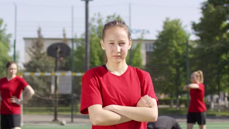 Zuversichtliche-Fußball-Mädchen-posiert-mit-Armen-gekreuzt-auf-Outdoor-Feld