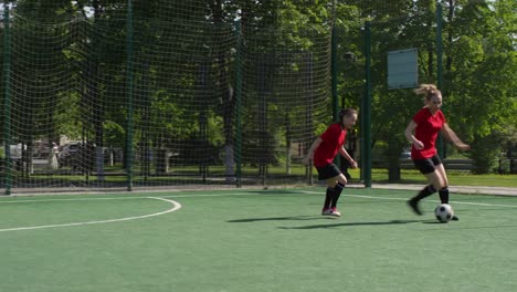 Junge-Sportlerinnen-spielen-Fußball-auf-dem-Außenfeld