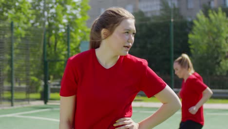 Junge-Fußballerin,-die-nach-dem-Training-Wasser-trinkt-und-sich-ausruht