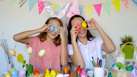 Mother-and-her-little-daughter-painting-eggs.-Happy-family-preparing-for-Easter.