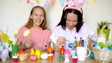 Mother-and-her-little-daughter-painting-eggs.-Happy-family-preparing-for-Easter.