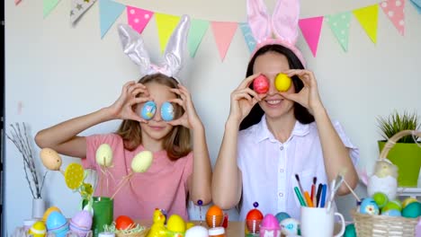 Mother-and-her-little-daughter-painting-eggs.-Happy-family-preparing-for-Easter.