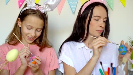 Mother-and-her-little-daughter-painting-eggs.-Happy-family-preparing-for-Easter.