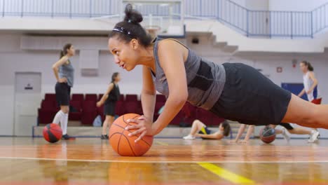 Chica-Africana-haciendo-flexiones-con-baloncesto-en-la-cancha-y-riendo