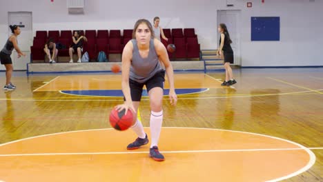 Young-Sportswoman-Looking-at-Camera-and-Dribbling-a-Basketball