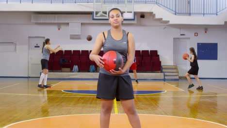 Zuversichtliche-afrikanische-Sportlerin-hält-Basketball-und-posiert-für-Kamera