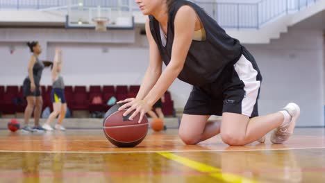 Atleta-joven-femenina-estirando-hacia-atrás-y-haciendo-flexiones-con-baloncesto