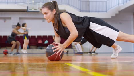 Junges-Mädchen-macht-Pushups-mit-Basketball-beim-Training-auf-dem-Platz