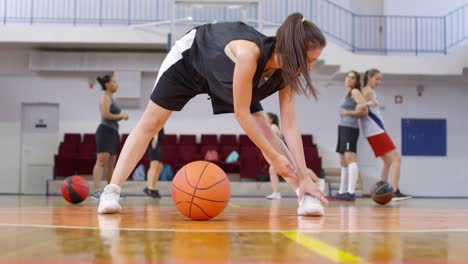 Junge-Basketballspielerin-dehnt-Beine-auf-dem-Platz