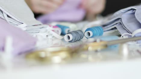 Close-up-of-accessories-for-sewing:-threads,-scissors,-fabric.-Woman-sews-medical-masks-at-home.