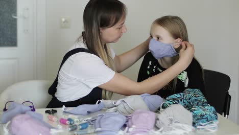 Una-joven-madre-viste-a-su-hija-con-una-máscara-médica-cosida.