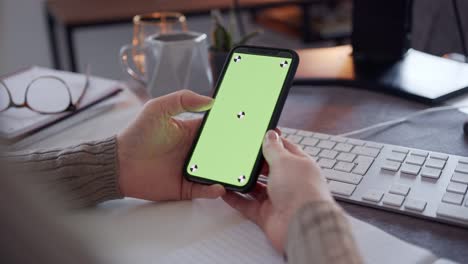 Anonymous-Woman-Using-A-Smart-Phone-With-a-Green-Screen-On-a-Desk