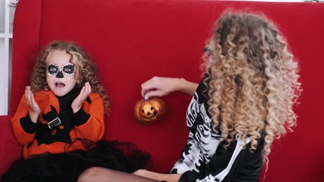 Tochter-und-Mutter-in-Halloween-Kostüme-spielen-auf-rotem-Sofa