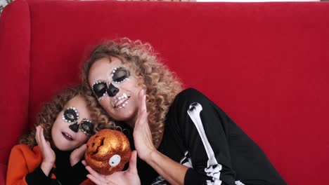 Daughter-and-mom-in-halloween-costumes-play-on-red-sofa