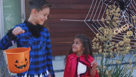 Portrait-Of-Two-Children-Wearing-Fancy-Dress-Outside-House-Collecting-Candy-For-Trick-Or-Treat