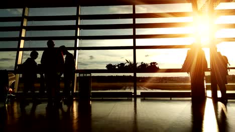 Silhouetten-von-Passagieren-in-der-Flughafenlounge-bei-Sonnenuntergang