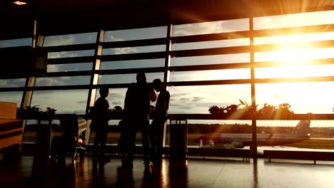 Silhouetten-von-Passagieren-in-der-Flughafenlounge-bei-Sonnenuntergang