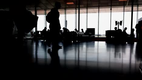 Silhouettes-of-passengers-in-the-airport-lounge-during-sunset