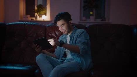 Happy-and-Positive-Asian-guy-win-played-in-game-on-tablet-at-home-on-sofa.