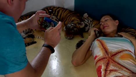 Frau-liegt-mit-dem-Tiger-Cubs.-Mann-nimmt-Bilder-auf-dem-Handy