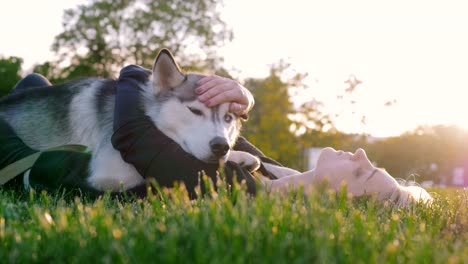 Schöne-junge-Frau,-die-das-Spiel-mit-lustigen-husky-Hund-draußen-im-park