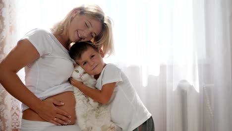 future-mother-with-cute-boy-holding-in-hand-pet-on-background-of-white-curtains-in-room