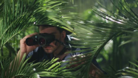 Abenteurer-in-Hut-Regenwald-spazieren-und-schauen-durch-ein-Fernglas