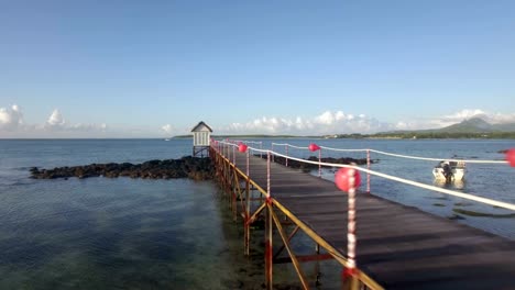 Aerial-view-of-coast-line-of-Mauritius-Island,-water-laves,-camera-moves-along-pear-in-sea-against-sky