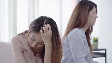 Unhappy-Asian-lesbian-lgbt-couple-sitting-each-side-of-sofa-with-moody-emotion-in-living-room.-Women-conflict-with-her-girlfriend-and-have-bad-relationship-at-home.