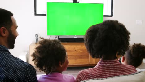 Vista-posterior-de-la-familia-sentada-en-el-sofá-en-casa-y-viendo-la-televisión